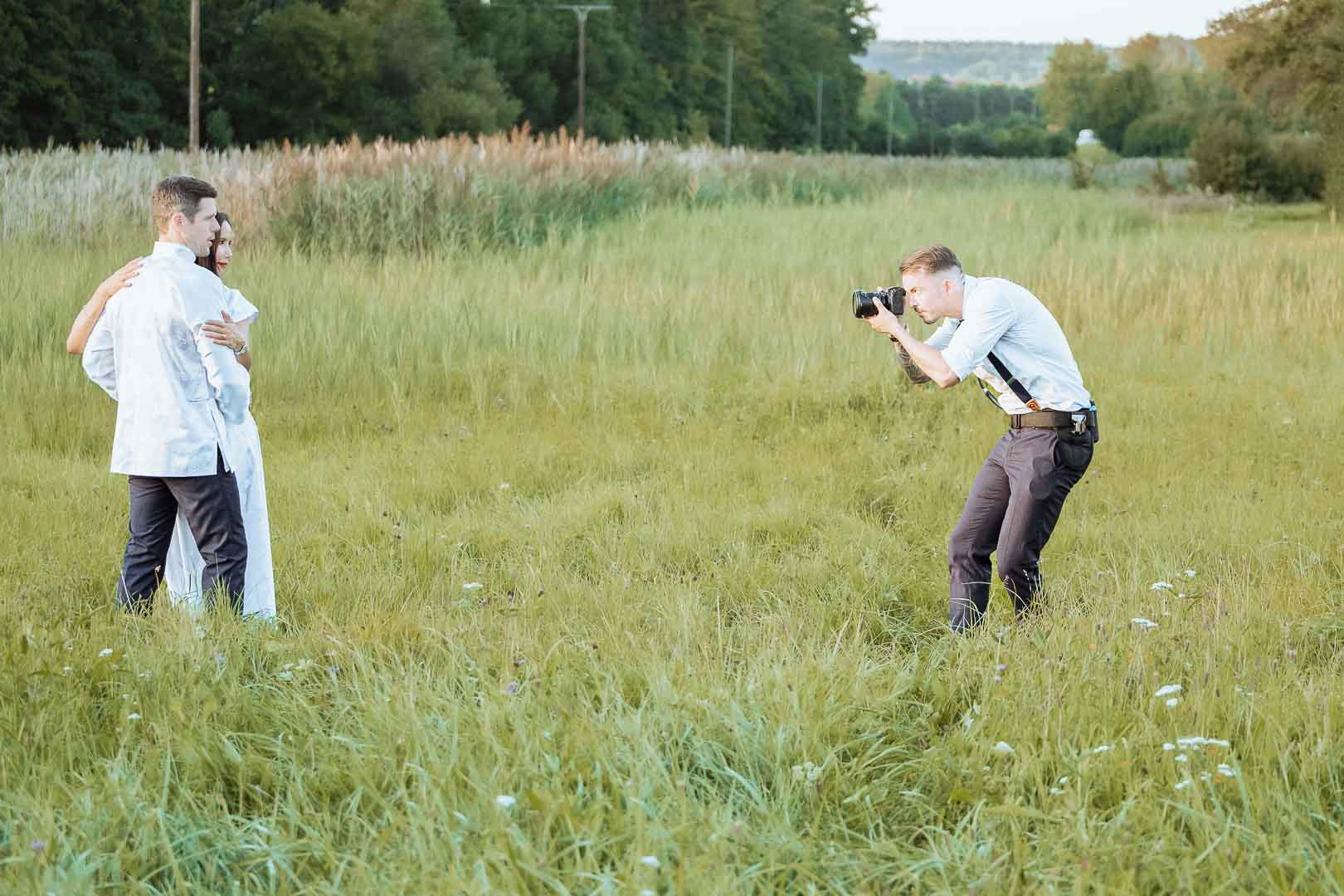 Hochzeitsfotograf macht von einem Brautpaar Fotos auf einer Wiese
