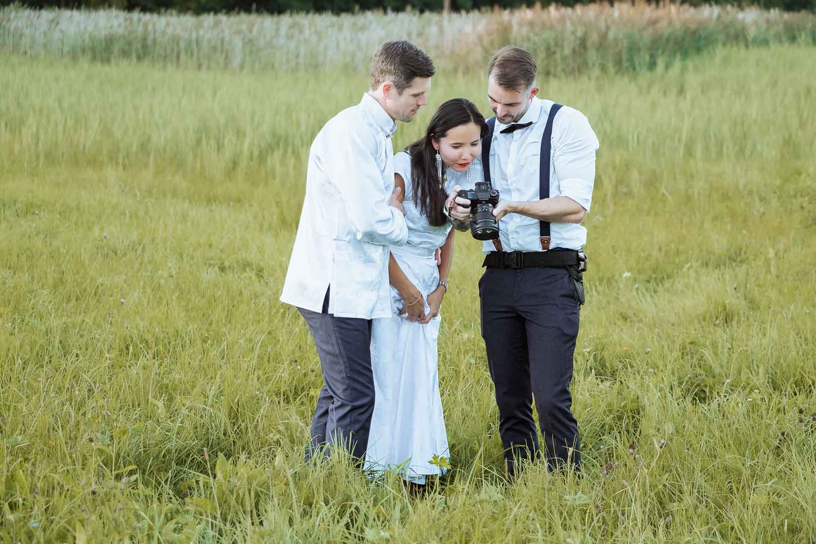 Hochzeitsfotograf zeigt einem Brautpaar Bilder auf seiner Kamera
